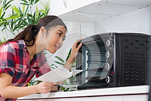 Lady looking at countertop oven holding instructions photo