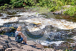 Lady looking at her smartphone next to a river in the summer photo
