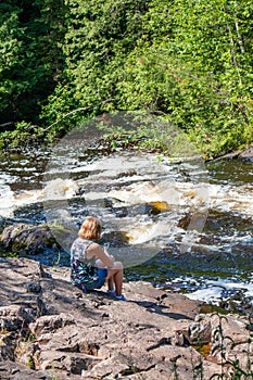 Lady looking at her smartphone next to a river in the summer photo