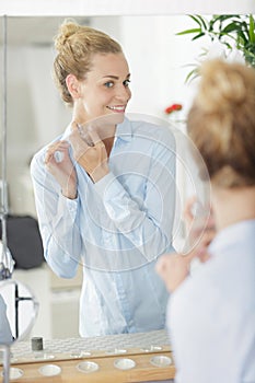 Lady looking in mirror as she applies perfume