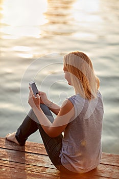 Lady looking in phone on dock