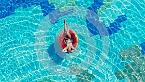 A lady is lying on a swim ring in the swimming pool. Carefree lady during summer holidays.