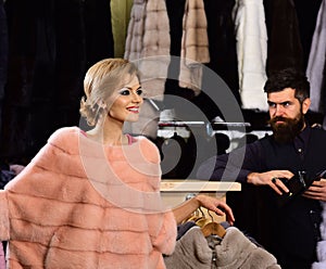 Lady and man with beard with fur coats on background.