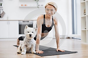 Lady in Phalakasana posing with furry pet in home interior