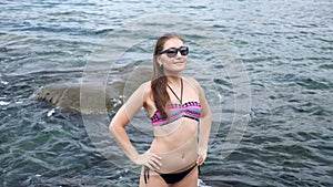 Lady poses standing against boundless ocean washing rocks