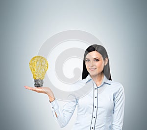 Lady presents a light bulb as a concept of new idea in business.
