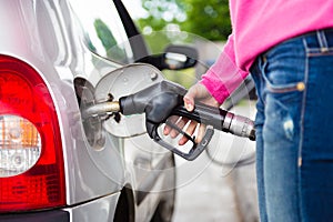 Lady pumping gasoline fuel in car at gas station. photo