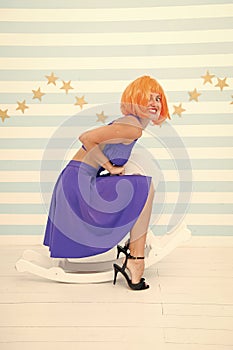 Lady red or ginger wig blue dress rides rocking horse. Comic and humorous concept. Woman playful cheerful mood having