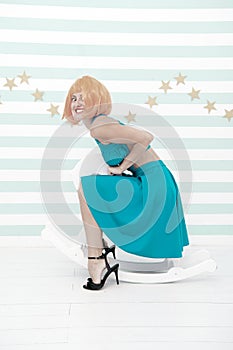 Lady red or ginger wig blue dress rides rocking horse. Comic and humorous concept. Woman playful cheerful mood having