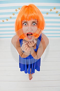 Lady red or ginger wig posing in blue dress. Comic actress concept. Woman playful mood having fun. Fun and entertainment