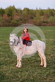 Lady riding a girl child in a dress riding a white horse