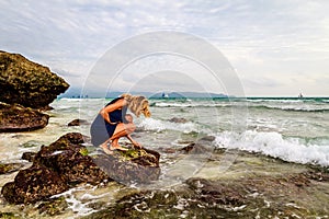 Lady on rocks on the coast, Boracay Island, Philippines