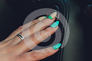 Lady`s hand pressing on car`s engine start button.