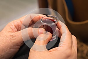 A lady`s hands hold a red wine cup in Holy Communion