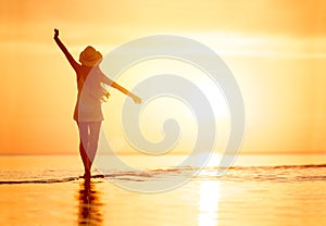 Lady`s silhouette with raised arms sunset beach photo