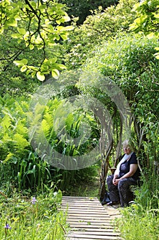Lady sat in natural arbour in garden
