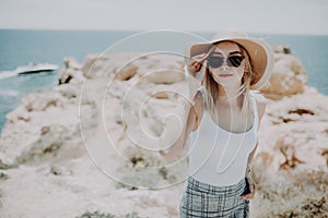 Lady at the sea. Attractive young woman on background of sea. Barefoot girl walking along the rocky beach