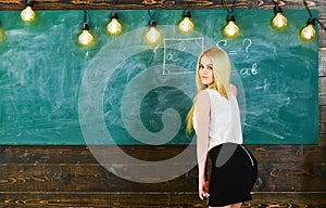 Lady teacher in short skirt looking back while explaining formula. teacher concept. Teacher of mathematics