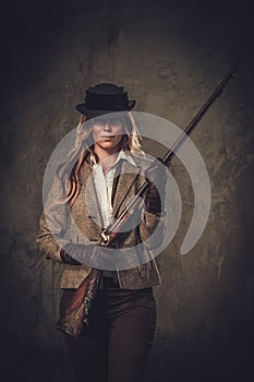 Lady with shotgun and hat from wild west on dark background.