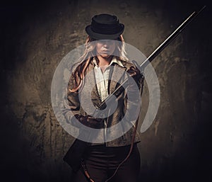 Lady with shotgun and hat from wild west on dark background.