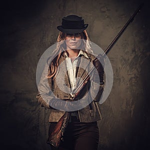 Lady with shotgun and hat from wild west on dark background.