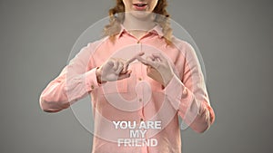 Lady signing you are my friend in asl, text on background communication for deaf