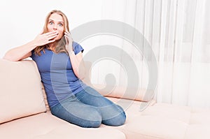 Lady sitting on couch talking at phone looking surprised