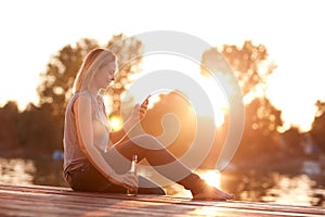 Lady sitting on dock near water at sunset