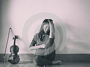 Lady sitting on ground floor,against on the wall,beside violin and bow,stress and tried feeling,vintage and art style