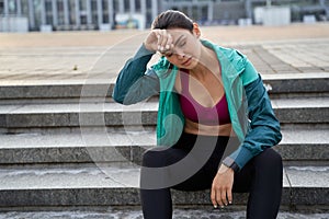 Lady sitting on the steps and resting after a workout