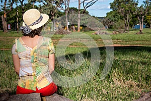 Lady Sitting on a Stump Wearing a Hat and Shorts Enjoying the Great Outdoors