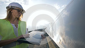 Lady solar engineer is closing her laptop and glancing into the camera