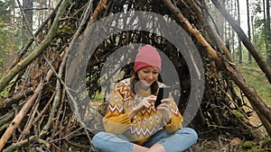 Lady surfs internet with phone sitting inside hut in wood