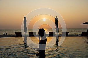 Lady on the swimming pool with background of twilight sunset