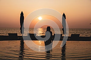 Lady on the swimming pool with background of twilight sunset