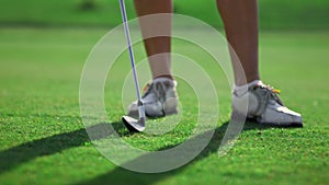 Lady swinging golf club on grass course. Woman legs posing on golfing fairway.