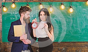 Lady teacher and strict schoolmaster care about discipline and rules in school. Man with beard hold book and girl