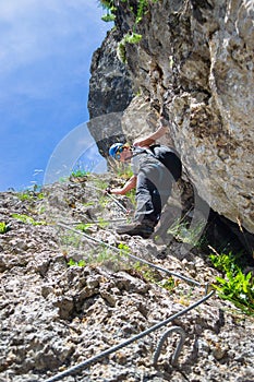 Lady tourist climbing via ferrata Astragalus in Bicaz Gorge Cheile Bicazului, Neamt county, Romania, on a bright sunny day.