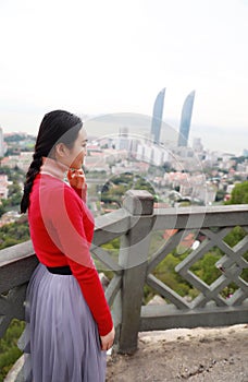 Lady tourist standing on a rock on the top of mountain and admire the view , Xiamen, China