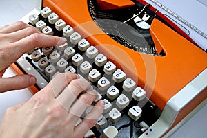 Lady typing orange vintage typewriter