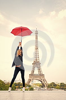 Lady with umbrella posing in front of Eiffel Tower, sky background. Lady tourist sporty and active walks in Paris city