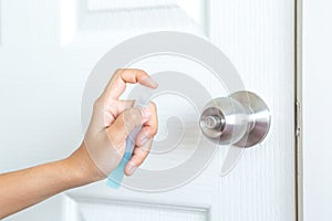 Lady using alcohol gel for spraying on the surface of door knob