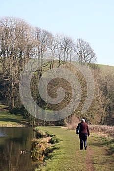 Lady walking along canal towpath in countryside