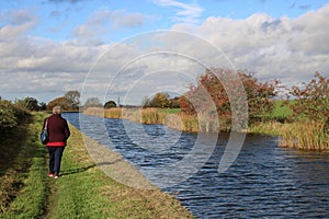 Lady walking on towpath on canal bank in autumn