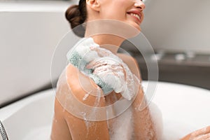 Lady Washing Body Using Sponge Taking Bath Sitting In Bathroom