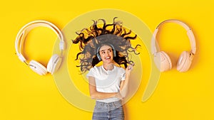 Lady Wearing Headphones Pointing Finger At Earphones Lying In Studio