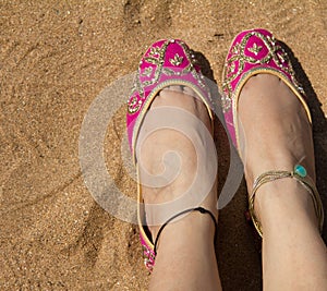 A lady wearing a pair of pink traditional Indian women`s shoes jutis at the Anjuna beach in Goa, India