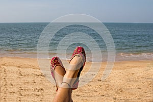 A lady wearing a pair of pink traditional Indian women`s shoes jutis at the Anjuna beach in Goa, India