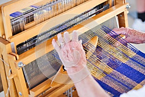 Lady weaving cloth on a traditional loom.