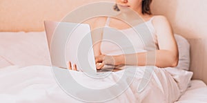 Lady working on a laptop in bed with white linens